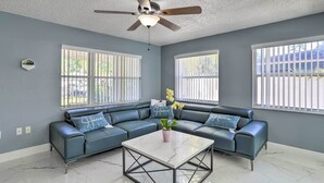 A living room with a sectional sofa, a marble coffee table, and a ceiling fan. - Modern Clearwater Home w/ Deck: 9 Mi to Beach (Clearwater)