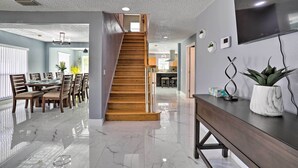 A modern interior with a wooden staircase, a dining area, and a kitchen. - Modern Clearwater Home w/ Deck: 9 Mi to Beach (Clearwater)