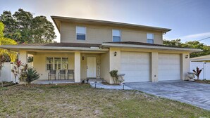 A two-story house with a garage, a covered front porch, and a small front yard with plants. - Modern Clearwater Home w/ Deck: 9 Mi to Beach (Clearwater)