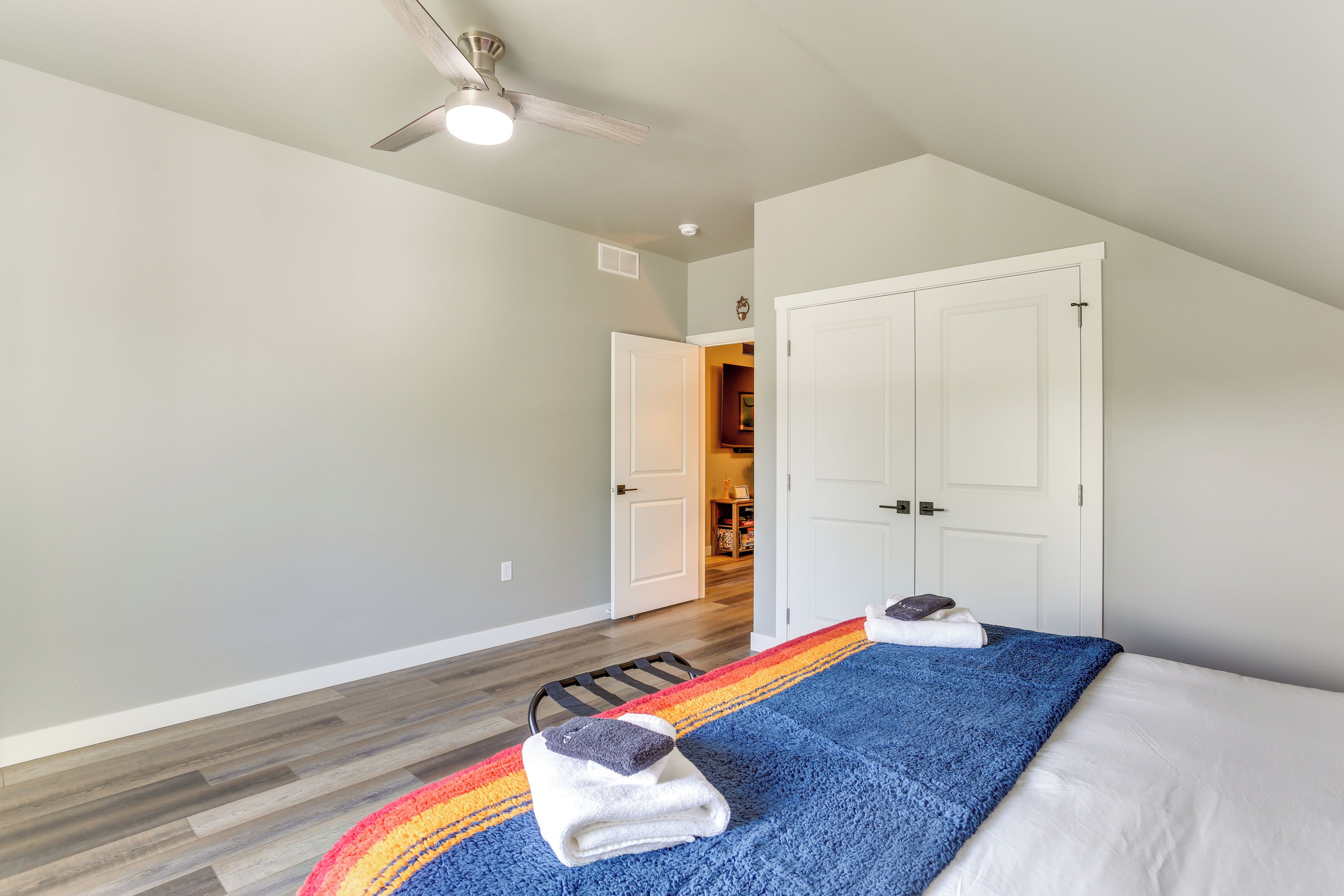 Un dormitorio con cama, ventilador de techo y un pasillo que lleva a otra habitación.