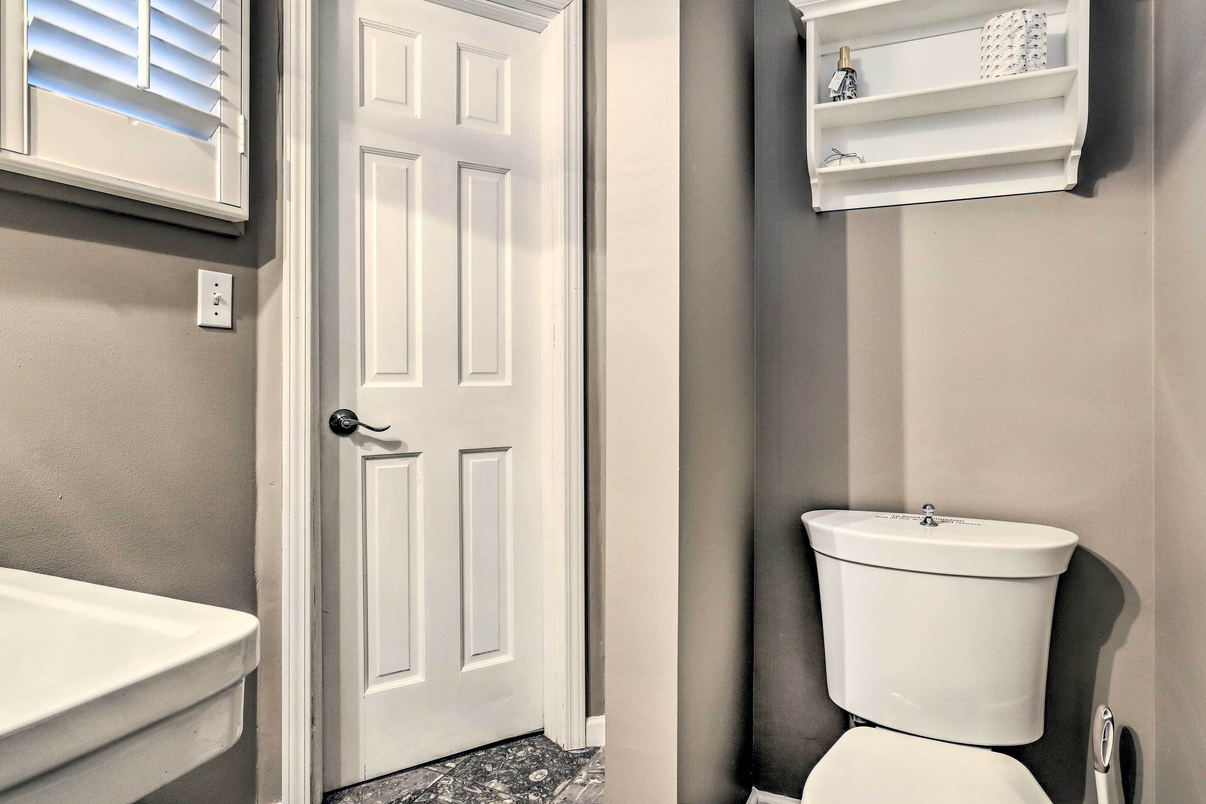 A bathroom with a white toilet, a white sink, and a white door.