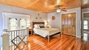 A bedroom with a wooden ceiling, a bed with white bedding, a nightstand, and a wooden wardrobe. - Lisle Apt: Fireplace & Stained Glass Windows! (Lisle)