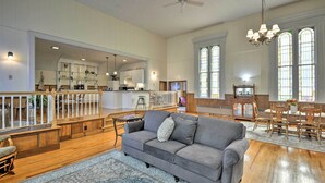 A spacious living room with a gray sofa, wooden flooring, and large windows. - Lisle Apt: Fireplace & Stained Glass Windows! (Lisle)
