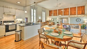 A spacious kitchen with a central island, wooden cabinets, and a dining area with a round table set for four. - Lisle Apt: Fireplace & Stained Glass Windows! (Lisle)