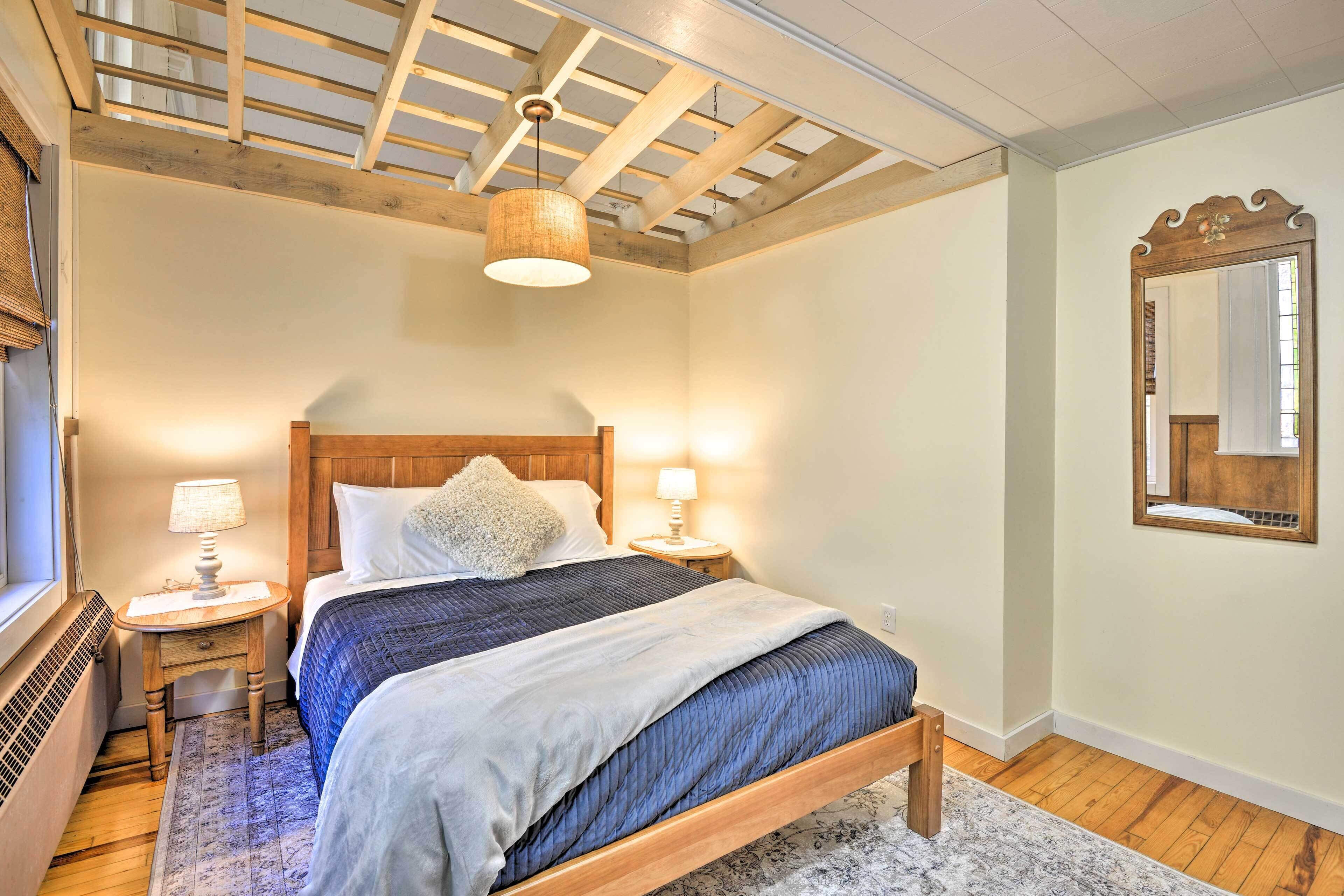 Ein Schlafzimmer mit einem hölzernen Bett, zwei Nachttischlampen, einem großen Spiegel und einem Oberlicht.