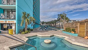 Un espace piscine avec un bâtiment bleu, des palmiers et un panneau indiquant « Shark Bites ».