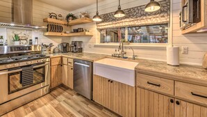 Una cocina moderna con armarios de madera, electrodomésticos de acero inoxidable e iluminación colgante.