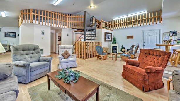 A spacious living room with a high wooden staircase, comfortable seating, and a small table with decorative items.