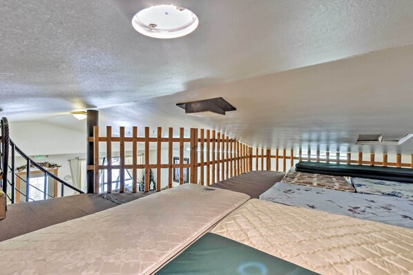 Une chambre d’hôtel avec un lit superposé, une cloison en bois, un luminaire au plafond et une vue sur l’extérieur.
