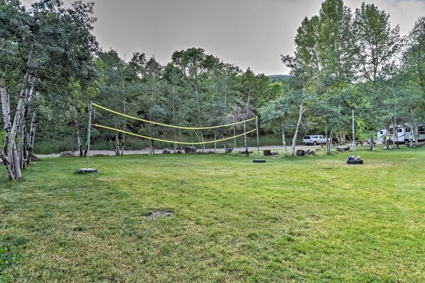 A grassy field with a yellow rope swing, trees, and RVs in the background. - Huge Preston Cabin w/ Game Room & Mountain Views! (Preston)