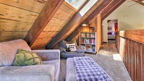 A cozy attic bedroom with a sloped ceiling, a built-in bookshelf, and a window providing natural light. - Near Trails: Cabin w/ 2-level Deck in Twain Harte (Twain Harte)