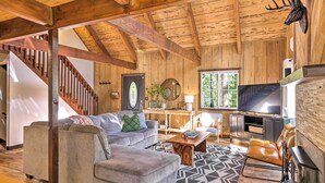 A wooden interior with a staircase, a grey sofa, a leather armchair, a TV, and a fireplace. - Near Trails: Cabin w/ 2-level Deck in Twain Harte (Twain Harte)