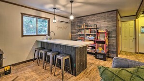 A kitchen with a bar area, wooden flooring, and a bookshelf with children's books. - Near Trails: Cabin w/ 2-level Deck in Twain Harte (Twain Harte)