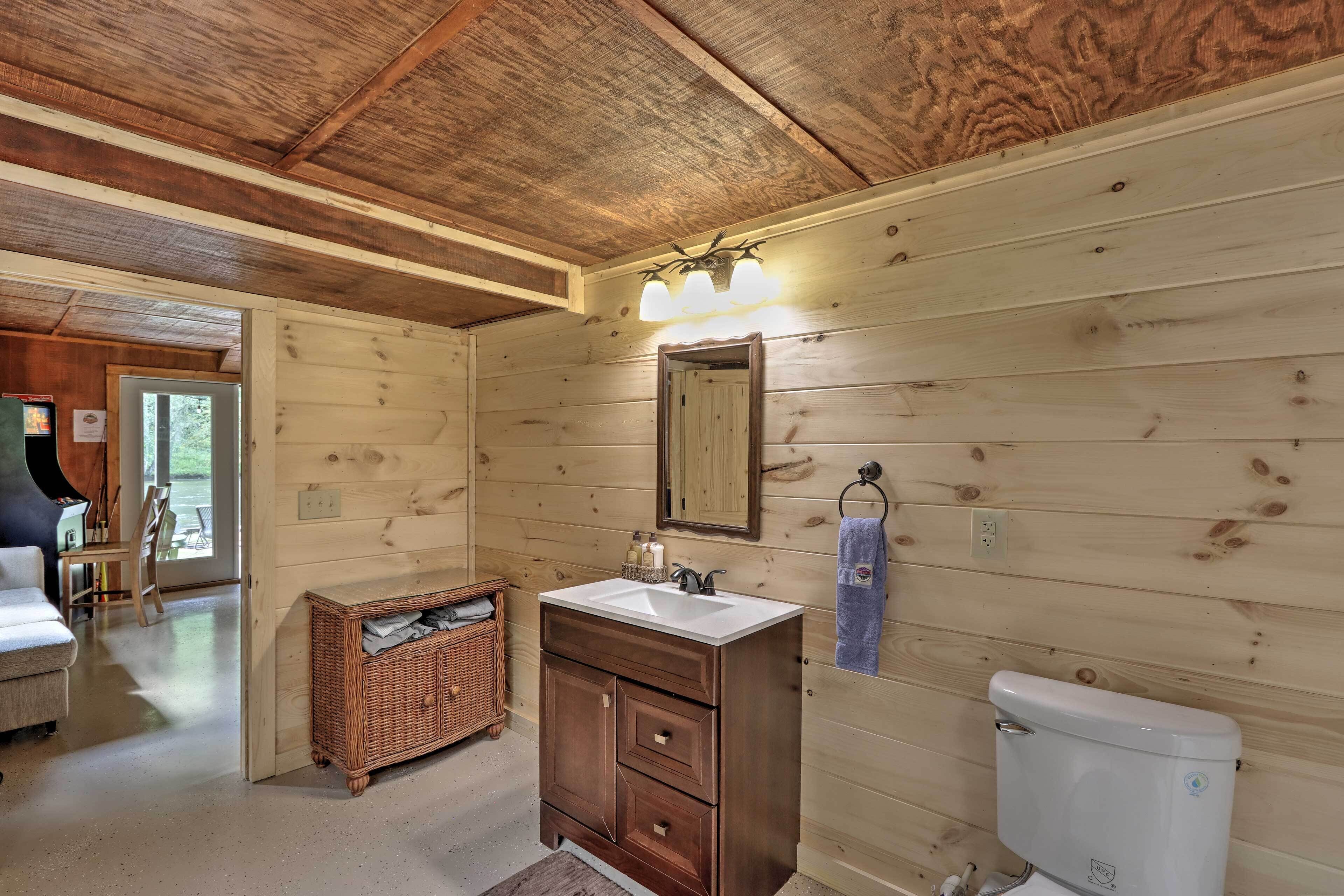 A wooden cabin bathroom with a white sink, dark wooden vanity, and a white toilet.