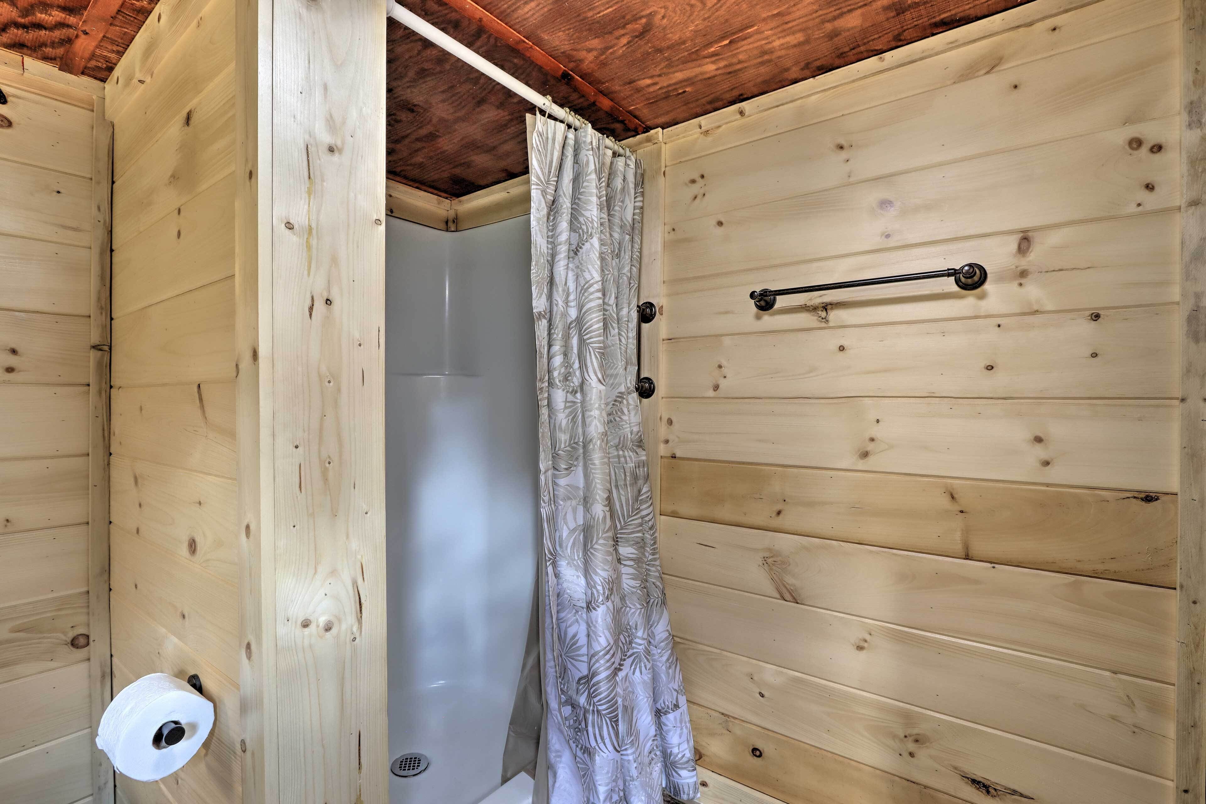 Ein Badezimmer einer Holzhütte mit Duschvorhang, Handtuchhalter und Toilettenpapierhalter.