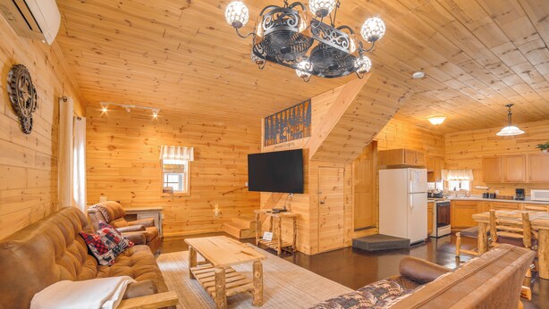 A wooden cabin interior with a living area, dining table, sofa, and kitchen. - 6 Mi to Shingleton: Manistique Home w/ Yard! (Manistique)