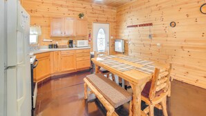 A wooden cabin interior with a kitchen, dining table, and bench. - 6 Mi to Shingleton: Manistique Home w/ Yard! (Manistique)
