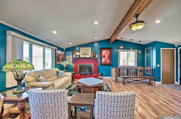 Una sala de estar amplia con chimenea, paredes azules y piso de madera.