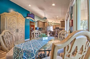 A dining area with a glass-top table, ornate chairs, and a patterned tablecloth.