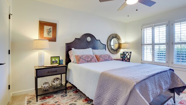 A bedroom with a bed, a ceiling fan, a nightstand with a lamp, a mirror, and a window with blinds. - Pool, Patio & Privacy! Home Near Georgetown Square (Georgetown)
