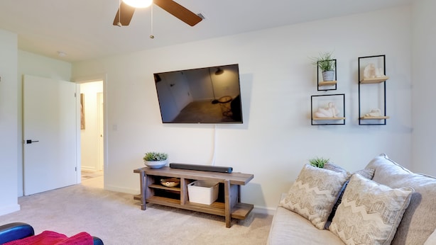 A living room with a ceiling fan, a flat-screen TV, a sofa, and a coffee table. - Pool, Patio & Privacy! Home Near Georgetown Square (Georgetown)