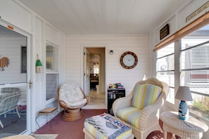 A cozy room with wicker furniture, a clock, and a view of the outside. - Lady Lake House w/ Lanai & Community Pool! (Lady Lake)