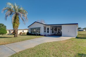 A single-story house with a covered porch, a garage, and a palm tree in the front yard. - Lady Lake House w/ Lanai & Community Pool! (Lady Lake)