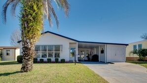 A single-story house with a covered garage, a lawn, and a palm tree. - Lady Lake House w/ Lanai & Community Pool! (Lady Lake)
