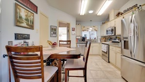 A modern kitchen with a dining area, featuring a wooden table, chairs, and a refrigerator. - Lady Lake House w/ Lanai & Community Pool! (Lady Lake)