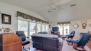 A living room with a black leather sofa, a wooden desk, and a television. - Lady Lake House w/ Lanai & Community Pool! (Lady Lake)