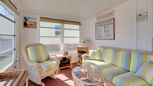 A cozy room with wicker furniture, a striped sofa, and a small table. - Lady Lake House w/ Lanai & Community Pool! (Lady Lake)