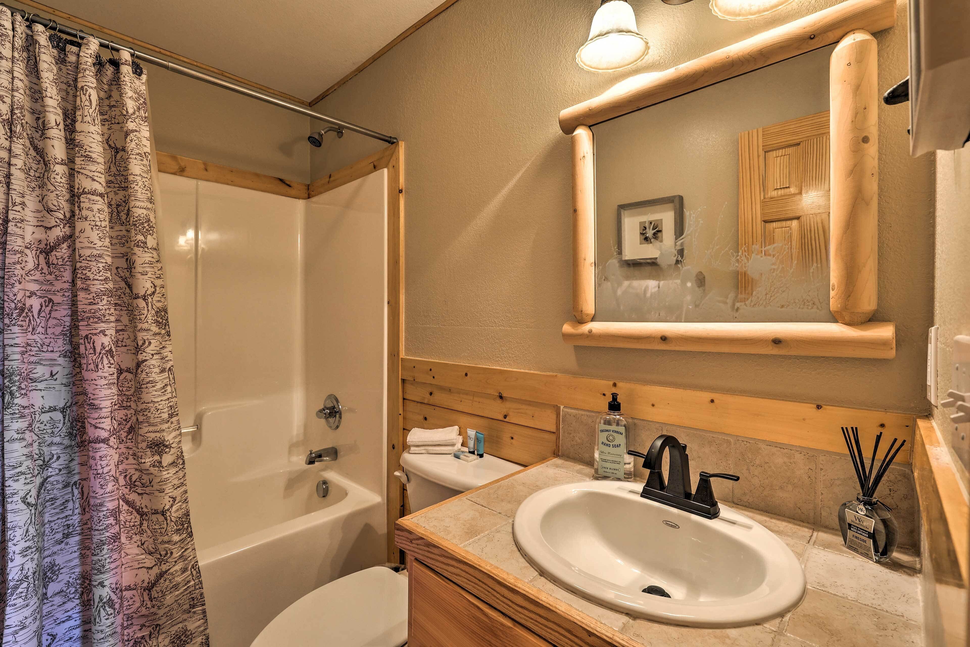 A bathroom with a bathtub, toilet, sink, and a mirror with a wooden frame.