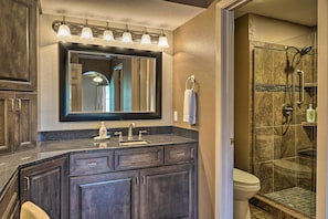 A bathroom with a dark wood vanity, a large mirror, a glass shower enclosure, and a white toilet. - Resort Condo in Branson: 4 Mi to the 76 Strip! (Branson)