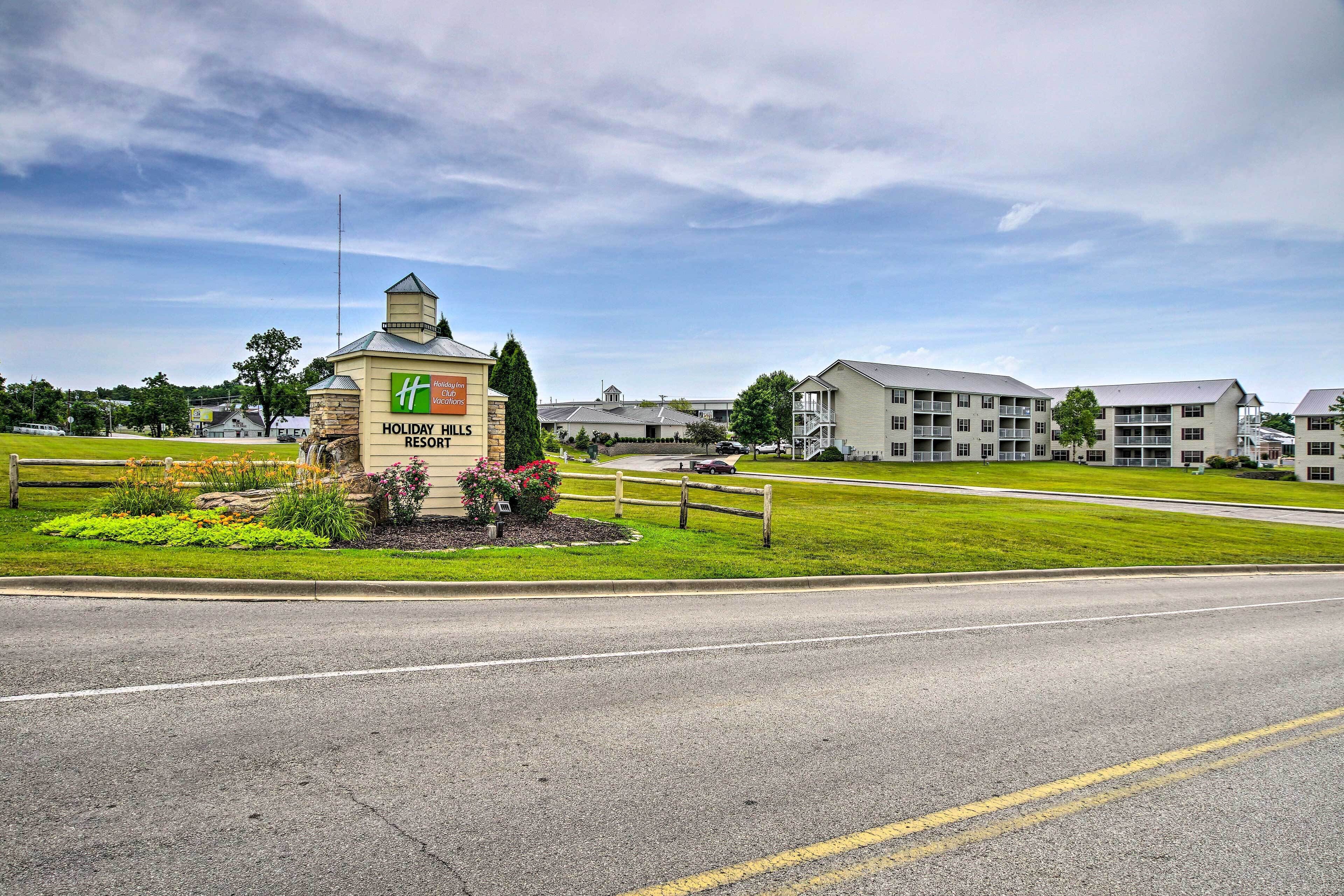 Señal de Holiday Inn Express, un área con césped y una valla de madera, y una carretera frente a un conjunto de edificios.