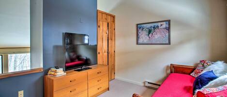 Un dormitorio con cama, cómoda de madera, televisor y un cuadro en la pared.