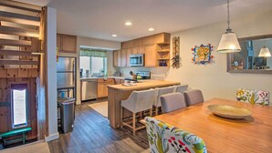Une cuisine moderne avec des meubles en bois, un îlot central et un coin repas comprenant une table et des chaises.