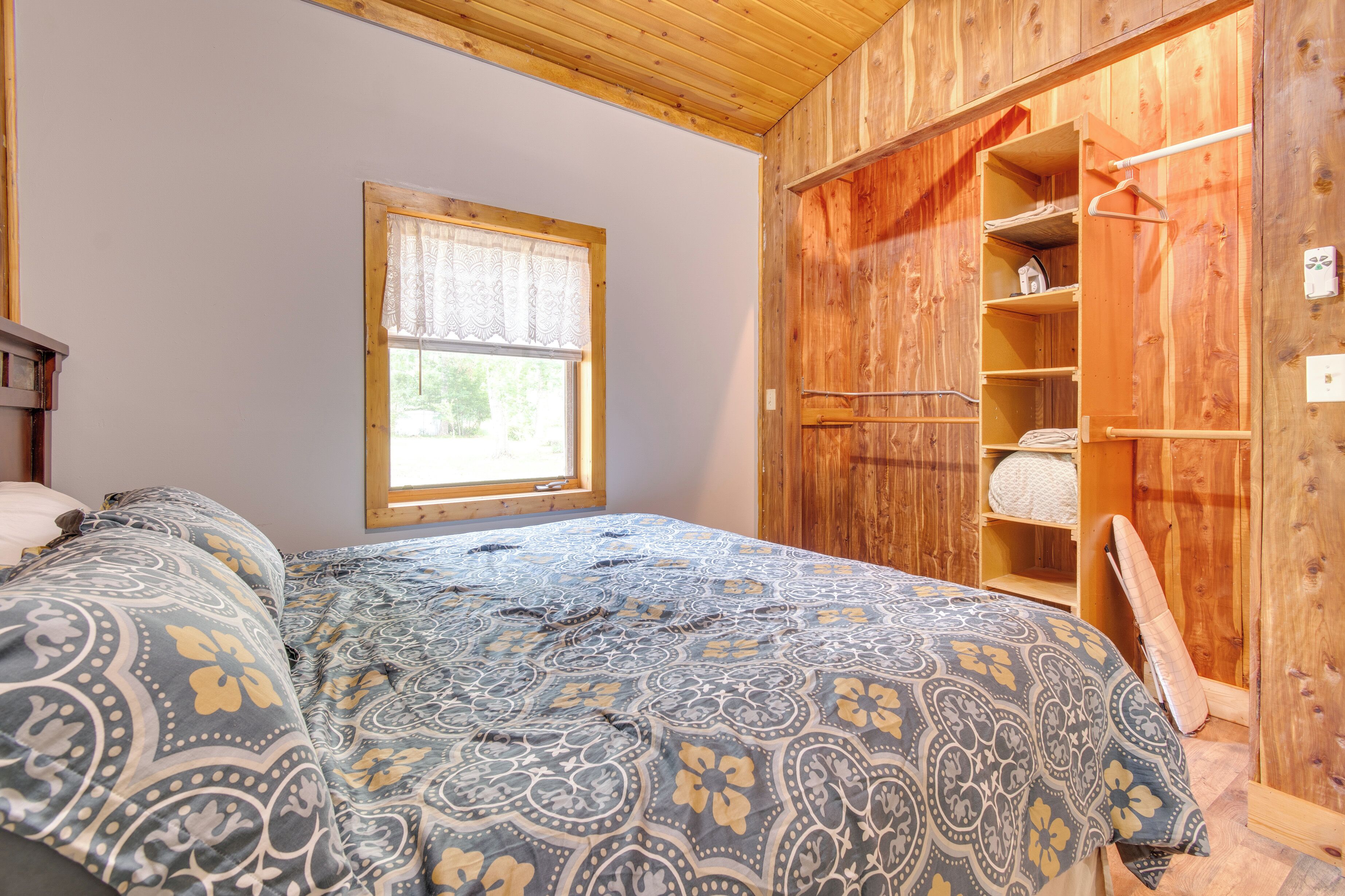 Une chambre à coucher avec un lit, une fenêtre et une armoire en bois.