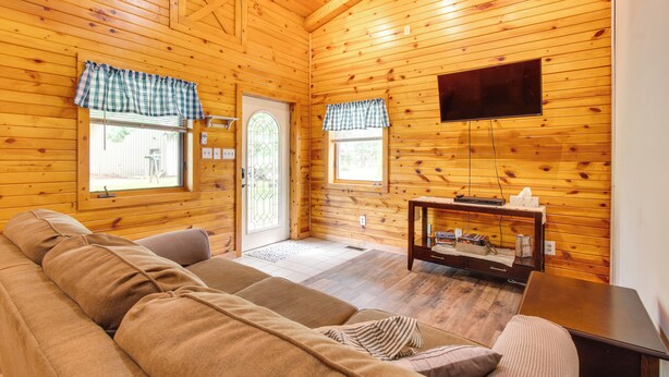 Ein gemütliches Holzhaus-Interieur mit einer Couch, einem Fernseher und einem kleinen Tisch.