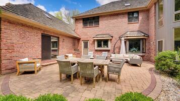 A patio with a brick house, outdoor furniture, and a small garden area.