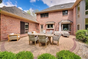 A patio with a brick house, outdoor furniture, and a small garden area. - Spacious & Secluded Madison Home Near Dtwn! (Madison)