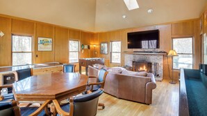 A spacious living room with a wooden floor, a large wooden dining table, leather sofas, and a fireplace. - Spacious & Secluded Madison Home Near Dtwn! (Madison)