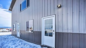 Un edificio de metal con puerta y ventanas blancas, rodeado de nieve.