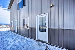 Un edificio de metal con puerta y ventanas blancas, rodeado de nieve.