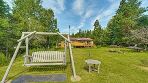 A wooden swing set, a small table, and a bench in a grassy yard with a house in the background. - 15 Mi to Duluth: Lake Superior Beachfront Home! (Duluth)