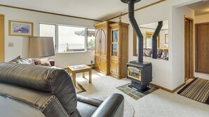 A living room with a sofa, a table, a cabinet, a fireplace, and a view through a window. - 15 Mi to Duluth: Lake Superior Beachfront Home! (Duluth)