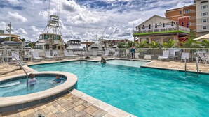 A swimming pool with a hot tub, lounge chairs, and a building with balconies in the background.