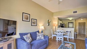 A living room with a sofa, TV, and a dining area with chairs and a table.