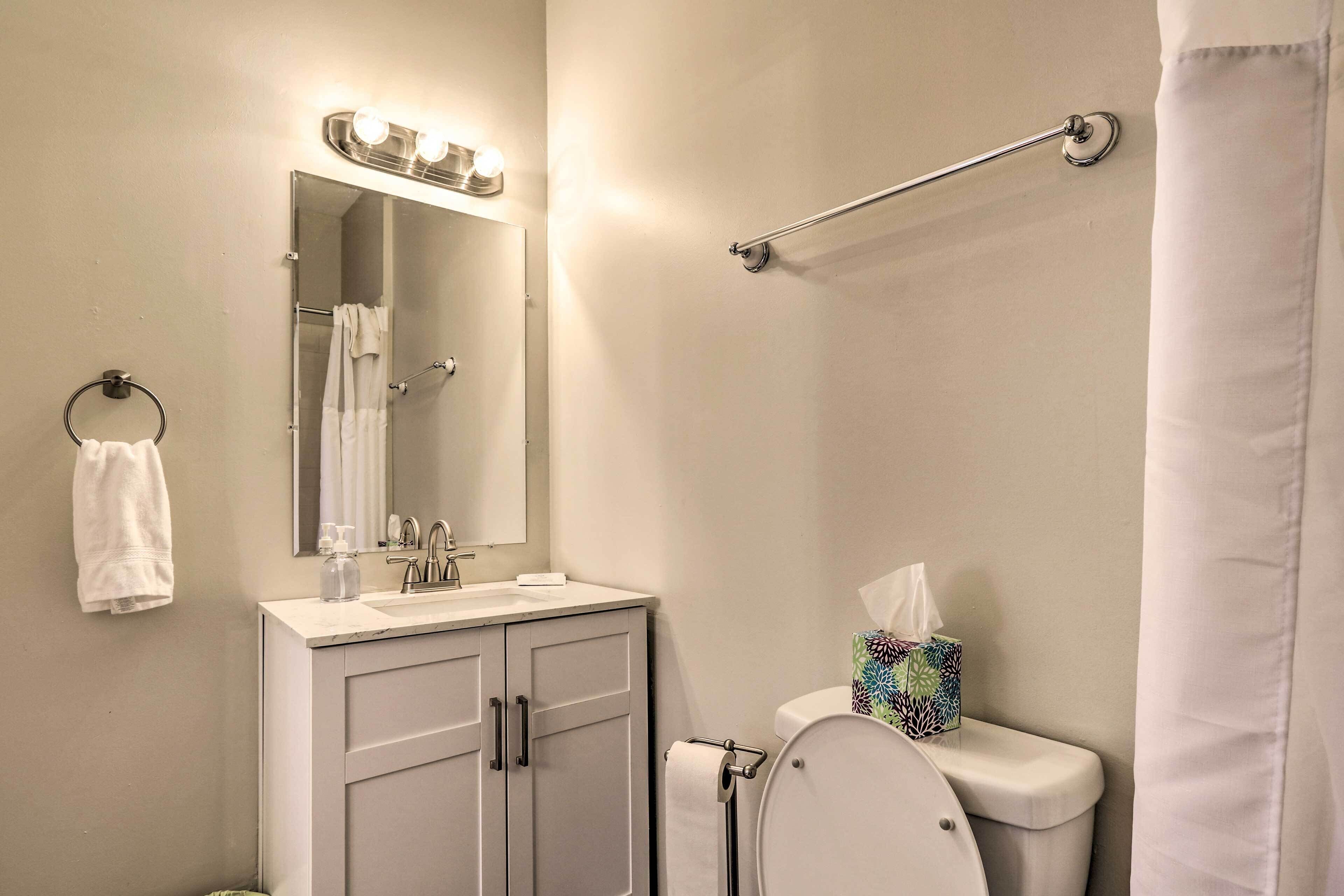 Un bagno con il water, un lavandino, uno specchio, un porta asciugamani e una tenda da doccia.