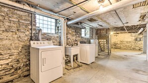 Une buanderie avec des murs en pierre, un lave-linge, un sèche-linge et un évier.