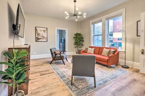 A living room with a large window, a sofa, a chair, a rug, and a plant. - Pet-friendly Condo w/ Deck ~ 3 Mi to Dtwn! (Cincinnati)